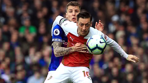 Everton’s Lucas Digne, behind, and Arsenal’s Mesut Ozil battle for the ball during their English Premier League soccer match on April 7, 2019.