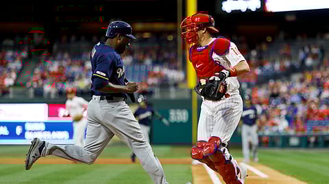 Brewers’ Lorenzo Cain scores as he passes  Phillies catcher J.T. Realmuto in the first inning May 15  (Matt Slocum)