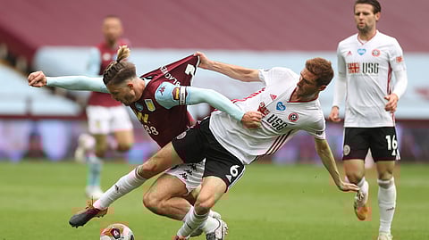 Aston Villa's Jack Grealish, left, challenges for the ball with Sheffield United's Chris Basham during the English Premier League soccer match between Aston Villa and Sheffield United at Villa Park in Birmingham, England, Wednesday, June 17, 2020. The English Premier League resumes Wednesday after its three-month suspension because of the coronavirus outbreak. 