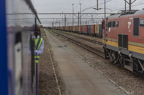 Transnet freight trains pass shipping containers at the Transnet SOC Ltd. Sentrarand depot, in the Benoni district of Gauteng, South Africa.