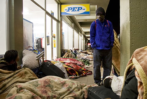 People camp out and take shelter on the streets near a police station after they left a settlement in Primrose, near Johannesburg, South Africa