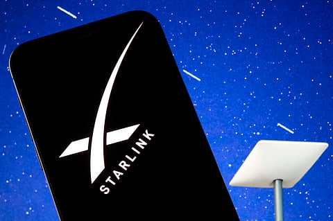 The SpaceX Starlink logo is seen displayed on a smartphone screen, with a Starlink satellite dish visible in the background, in this photo illustration taken on July 24, 2026. (Photo by Matteo Della Torre/NurPhoto via Getty Images)