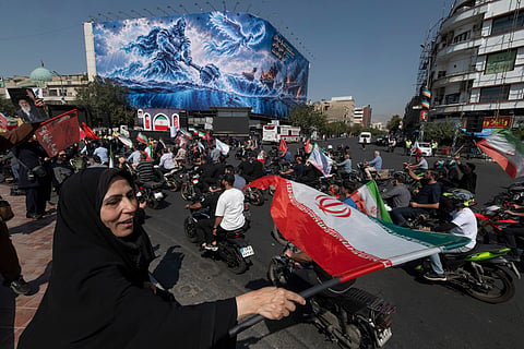 A veiled pro-government supporter waves an Iranian national flag as motorcyclists from Iran's Self-Sacrificing Forces ride during a rally in Tehran, Iran, on September 25, 2026, amid escalating tensions between Iran and the United States. (Photo by Morteza Nikoubazl/NurPhoto via Getty Images)
