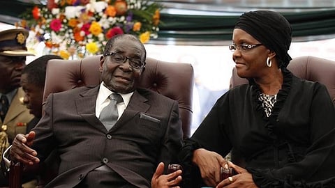 Zimbabwe President Robert Mugabe (L) speaks to his wife Grace during the funeral of his sister, Bridget, in the village of Zvimba, 90 km (55 miles) west of Harare January 21 2014.      REUTERS/Philimon Bulawayo