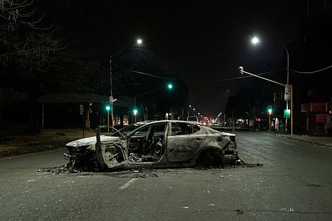 A burnt car is seen in a street where protests have been taking place in Jeppestown, in Johannesburg on July 11, 2021.  Photographer: Emmanuel Corset/AFP/Getty Images