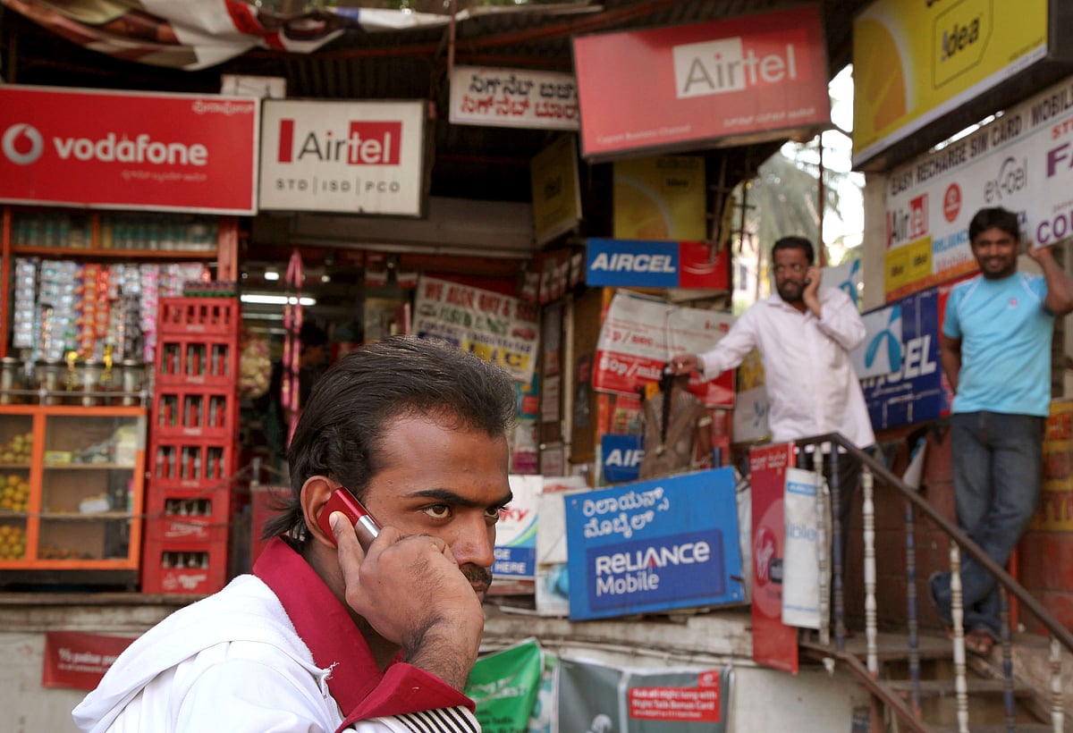 

A man speaks on a mobile phone in front of a shop selling pre-paid recharges for different mobile providers in Bengaluru (Photographer: Namas Bhojani/Bloomberg)