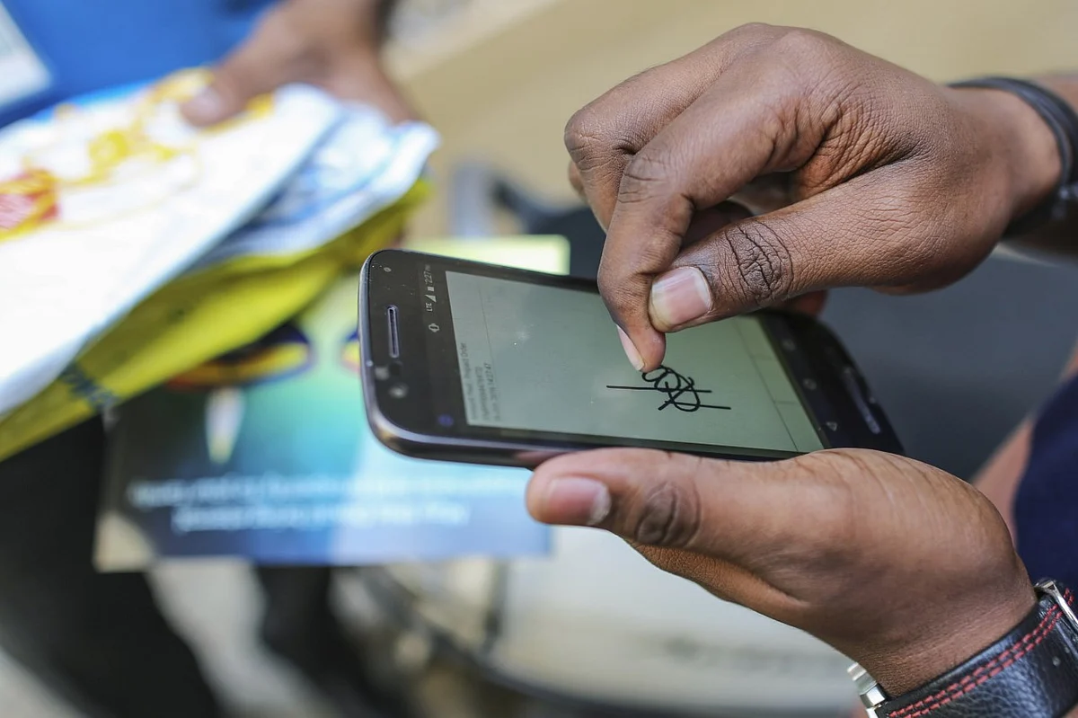 A customer signs for a package using a mobile phone (Photographer: Dhiraj SIngh)
