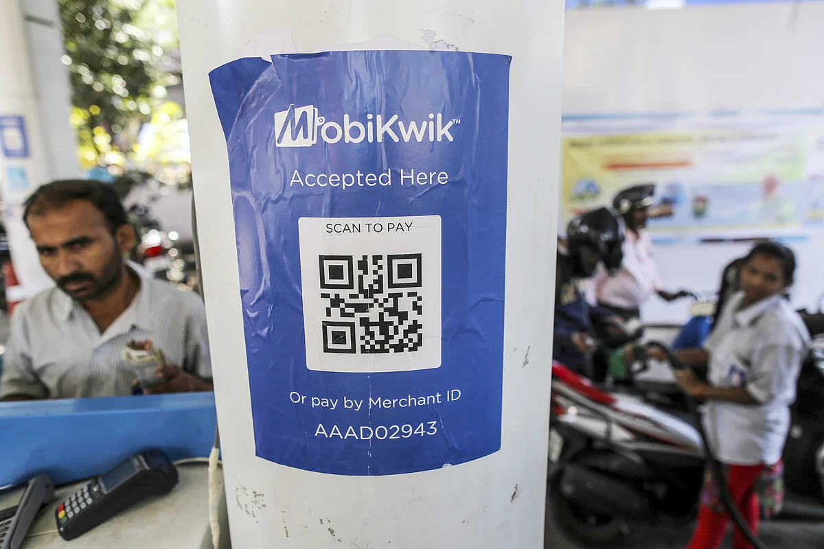 Motorists refuel their vehicles as a sign for digital payment service MobiKwik, operated by One MobiKwik Systems. (Photographer: Dhiraj Singh/Bloomberg)
