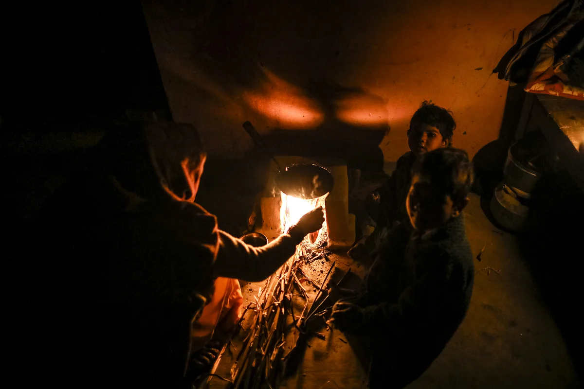 A woman cooks on a stove in the light provided by a kerosene lamp in her home at night in the village of Fateh Nagla, Uttar Pradesh, India, on January 14, 2017. (Photographer: Prashanth Vishwanathan/Bloomberg)