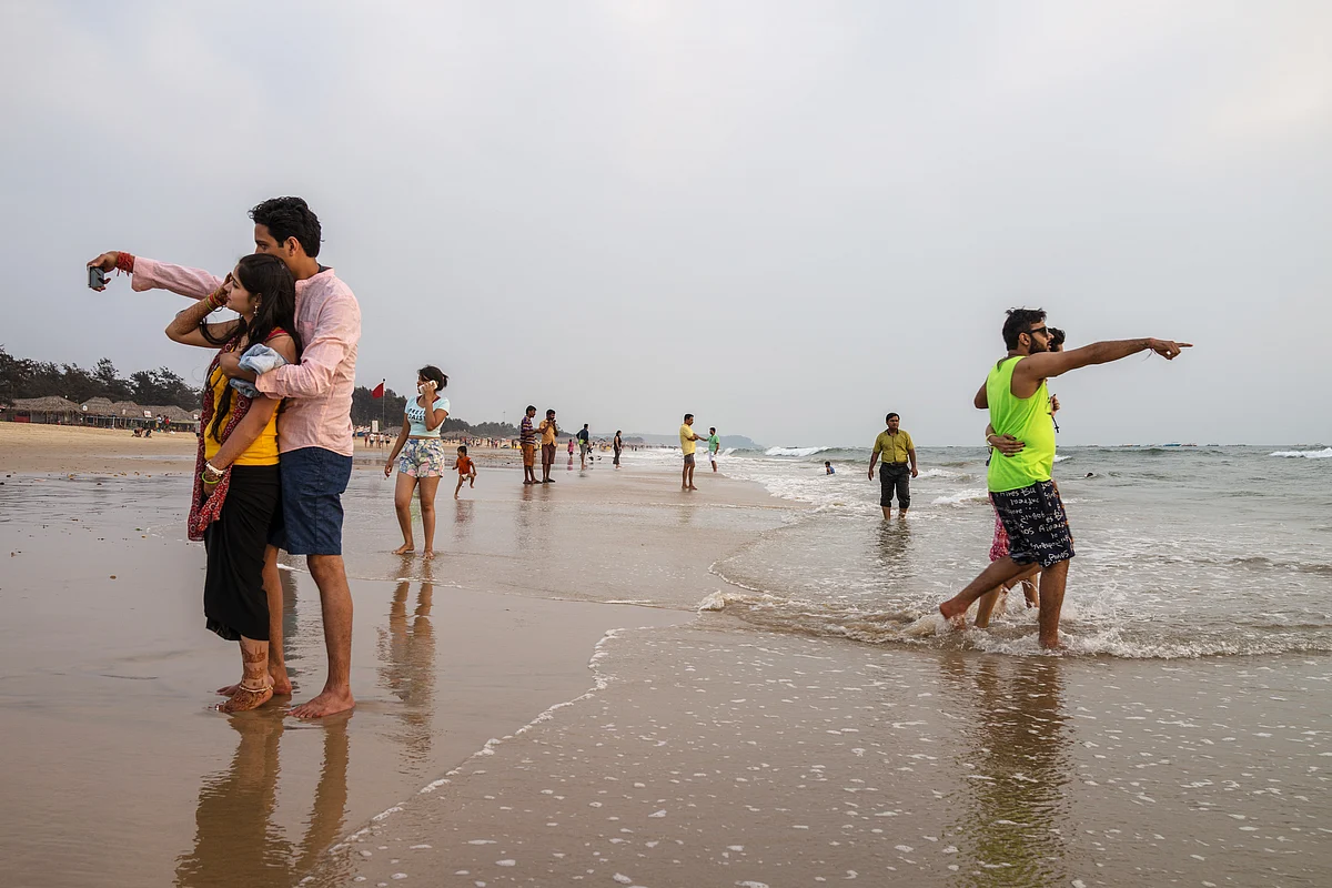 A couple take a selfie photograph as tourists and visitors gather at Baga beach in Bardez, Goa, India. (Photograph: Sanjit Das/Bloomberg)