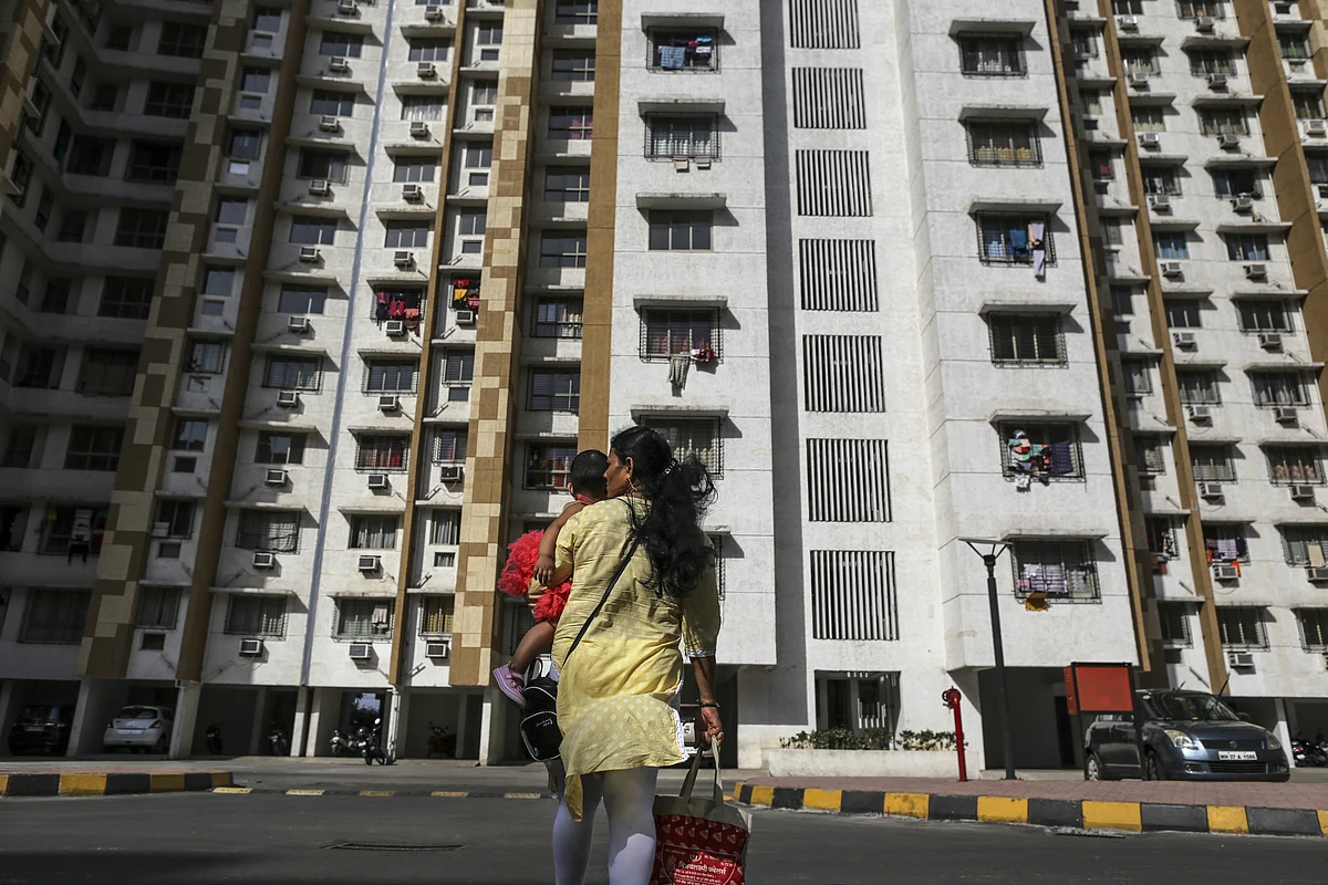 A pedestrian carries a child across a road in front of residential apartment buildings in Palava City on the outskirts of Mumbai. (Photographer: Dhiraj Singh/Bloomberg)