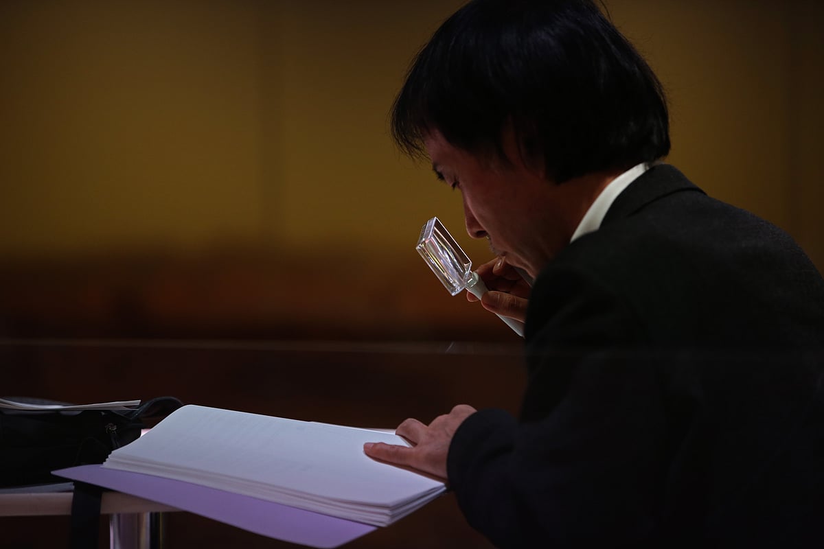

A person uses a magnifying glass to browse a document. (Photographer: Matthew Lloyd/Bloomberg)