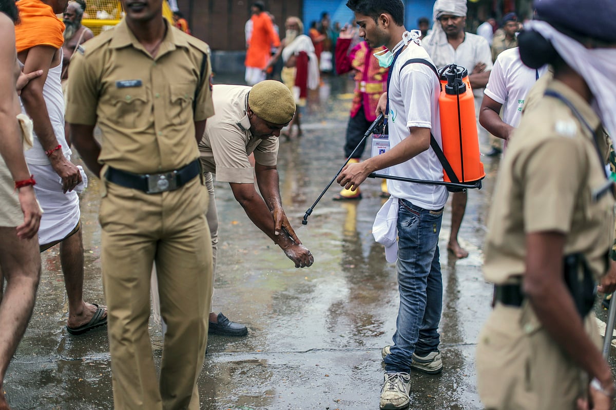 A street cleaner assists a police officer cleaning his hands in Nashik, Maharashtra, India. (Photographer: Dhiraj Singh/Bloomberg)