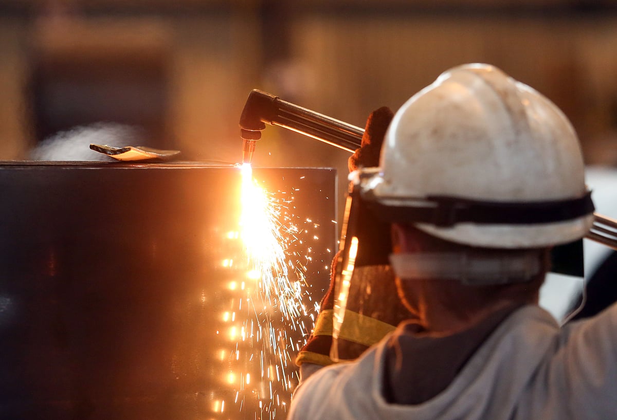 An employee cuts a sample from a roll of coiled steel inside a rolling steel mill. (Photographer: Chris Ratcliffe/Bloomberg)