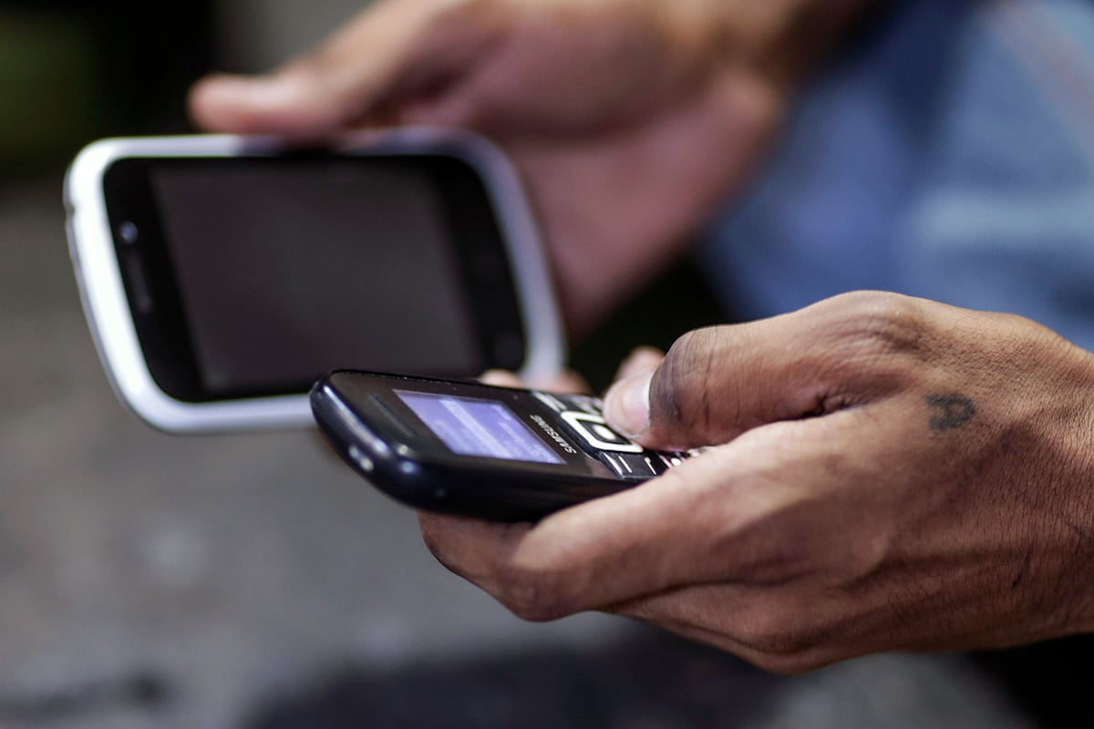 A man uses mobile phones in Mumbai. (Photographer: Dhiraj Singh/Bloomberg)