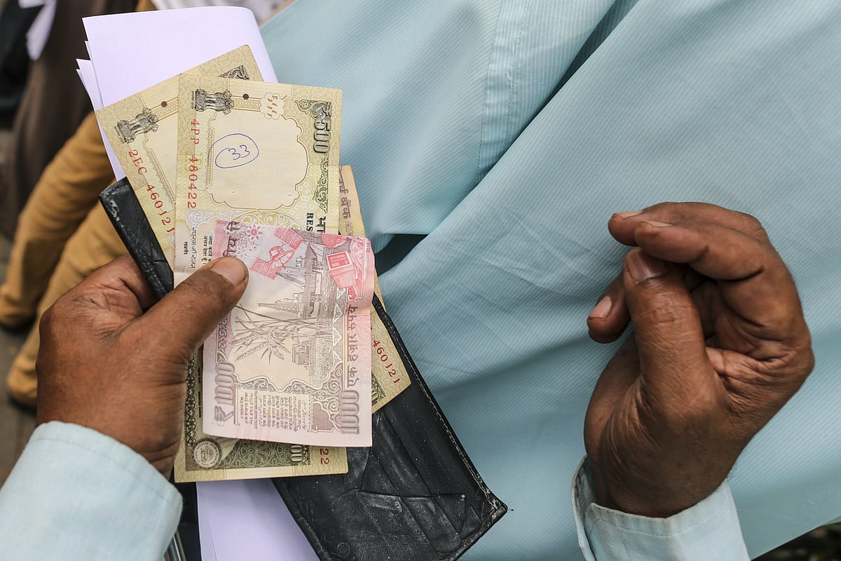 A man holds demonetised one thousand and five hundred rupee banknotes as he stands in a line in a post office in Mumbai. (Photographer: Dhiraj Singh/Bloomberg)