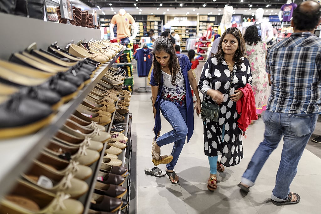 A customer tries on a pair of shoes at a Big Bazaar hypermarket. (Photographer: Dhiraj Singh/Bloomberg)