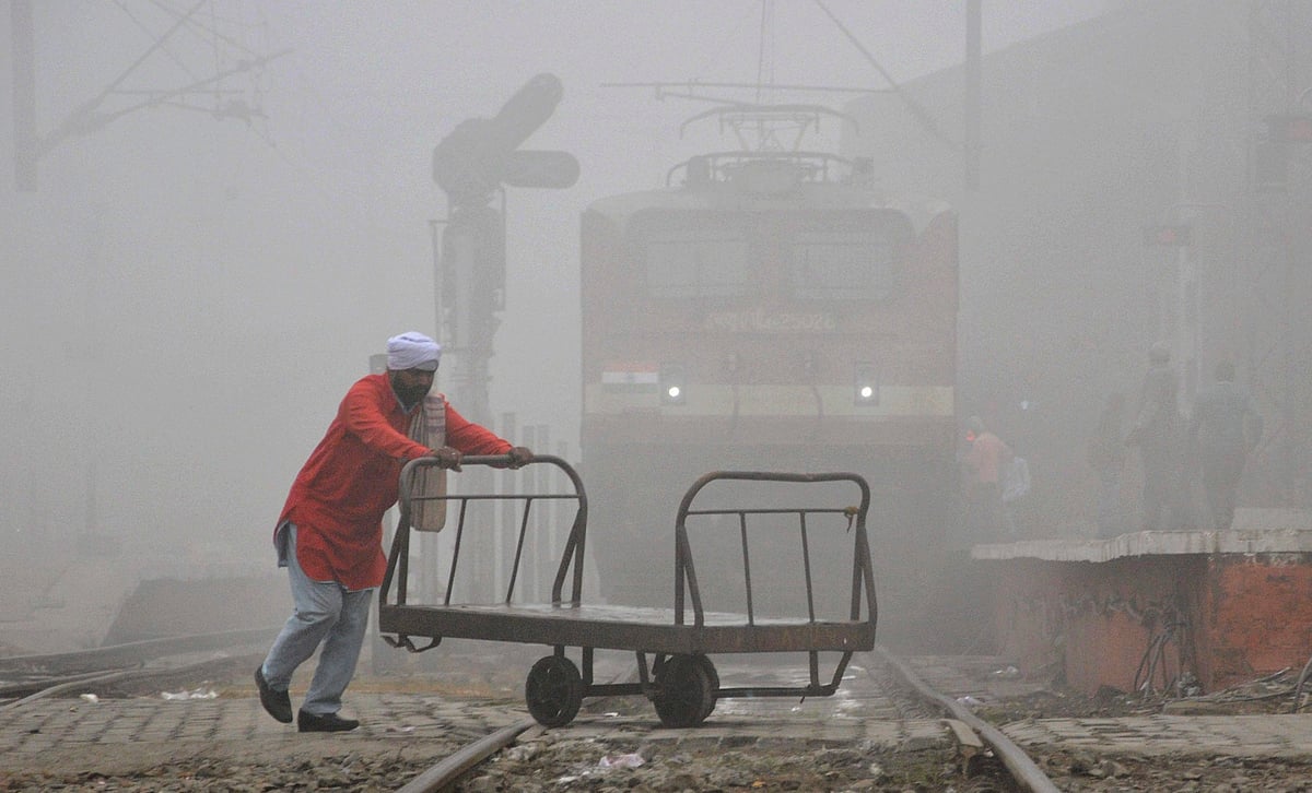 A porter crosses the railway tracks in dense fog at the railway station in Amritsar on Tuesday. (Source: PTI)