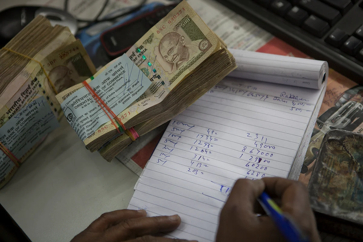 A cashier counts Indian rupee banknotes at an Oriental Bank of Commerce branch in New Delhi, India. (Photographer: Prashanth Vishwanathan/Bloomberg)