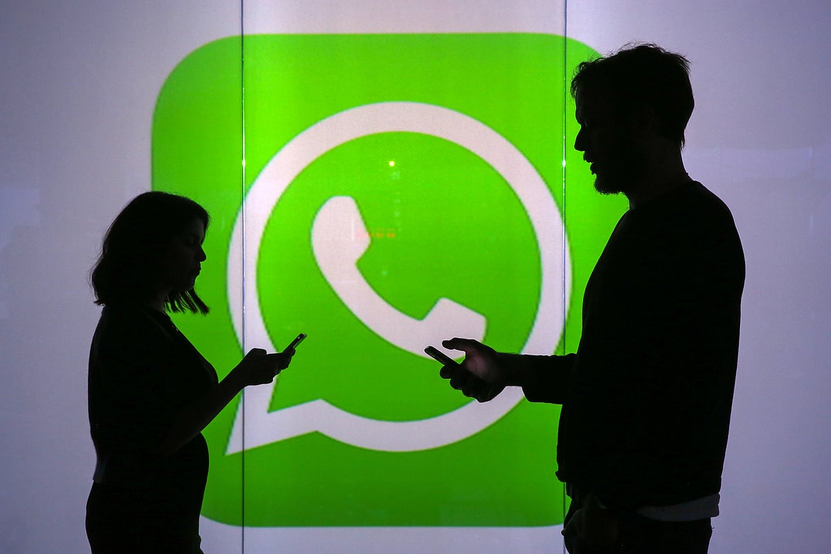 People are check mobile devices whilst standing against an illuminated wall bearing WhatsApp’s logo in this arranged photograph in London, U.K. (Photographer: Chris Ratcliffe/Bloomberg)