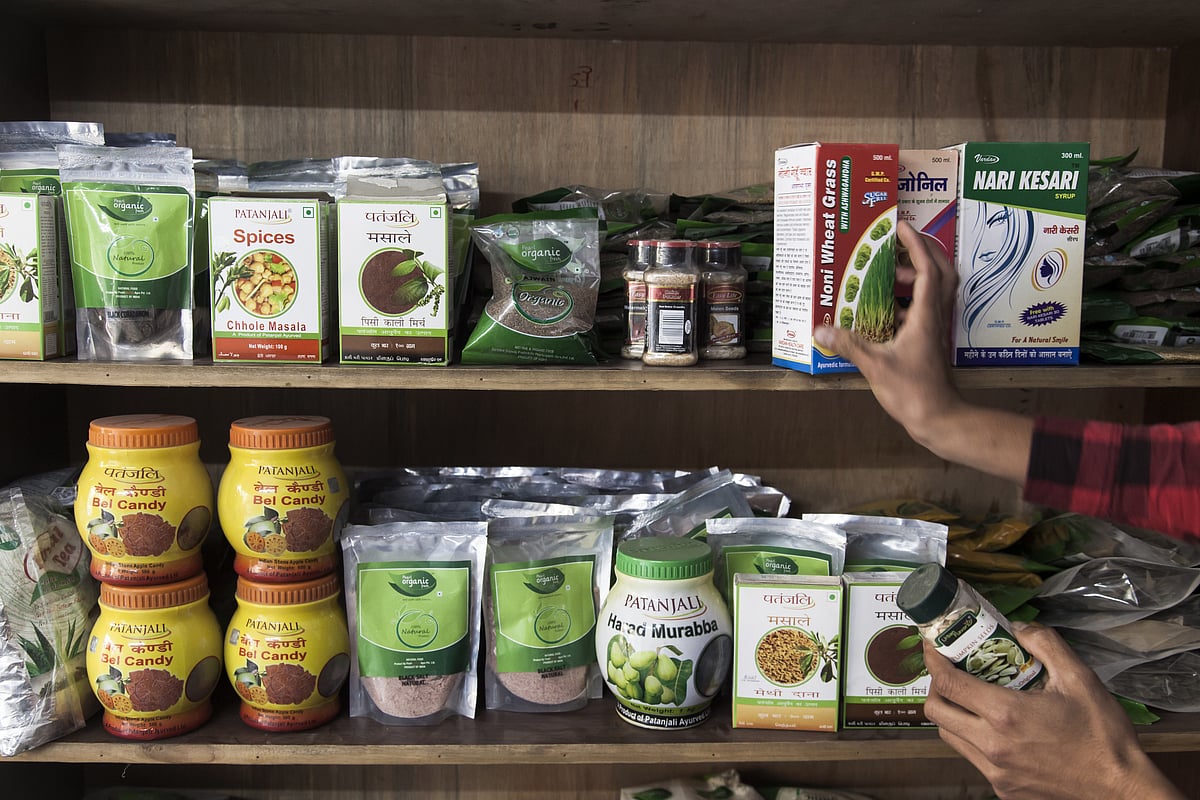 A customer holds a container of pumpkin seeds while picking out a box of wheat grass at a Patanjali Ayurved Ltd. store in New Delhi. (Photographer: Udit Kulshrestha/Bloomberg) &nbsp;