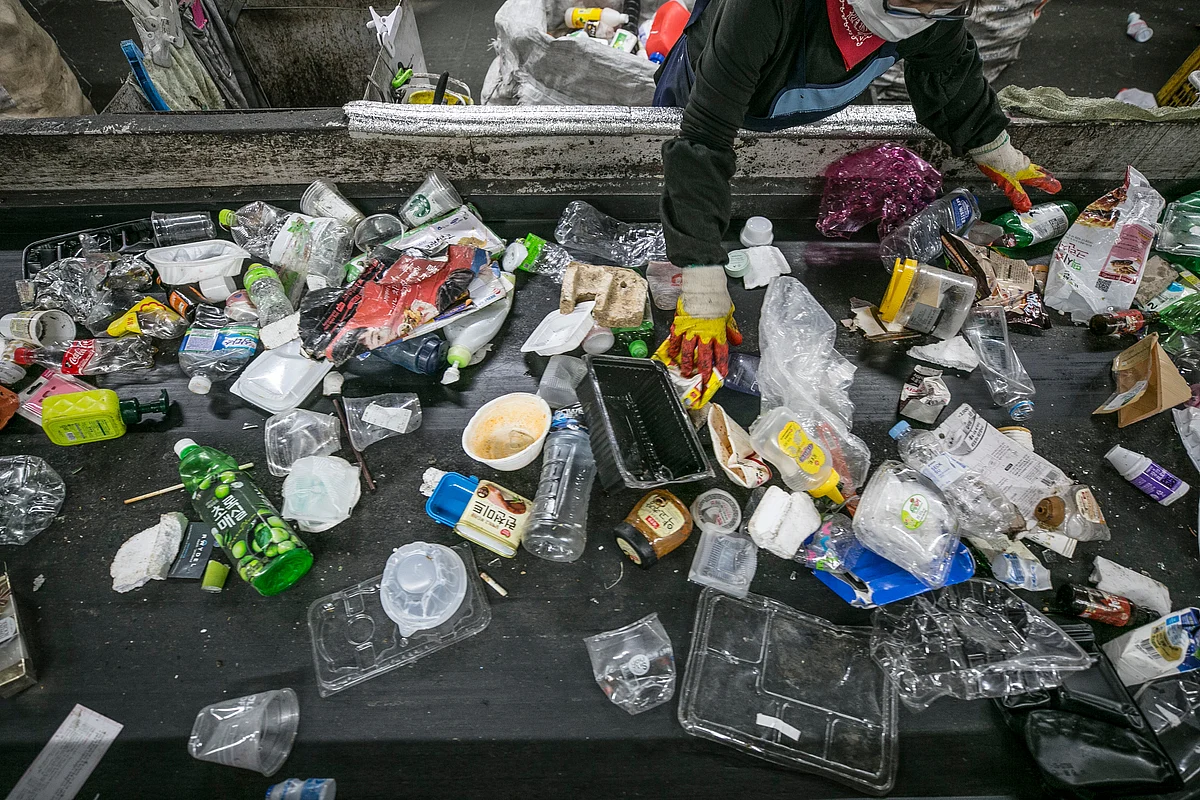 A worker separates plastic waste from other waste (Photographer: Jean Chung/Bloomberg) 