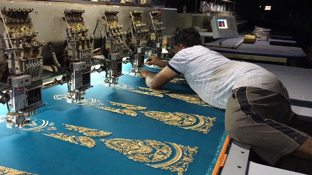 An embroidery worker threads the jari into the needle.