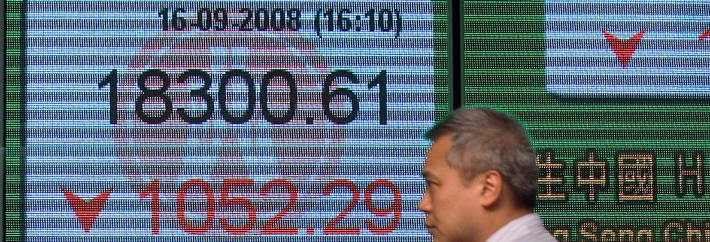 A man walks in front of an electronic board showing the closing figure of the Hang Seng Index in Hong Kong, on Sept. 16, 2008. (Photographer: Jerome Favre/Bloomberg News)