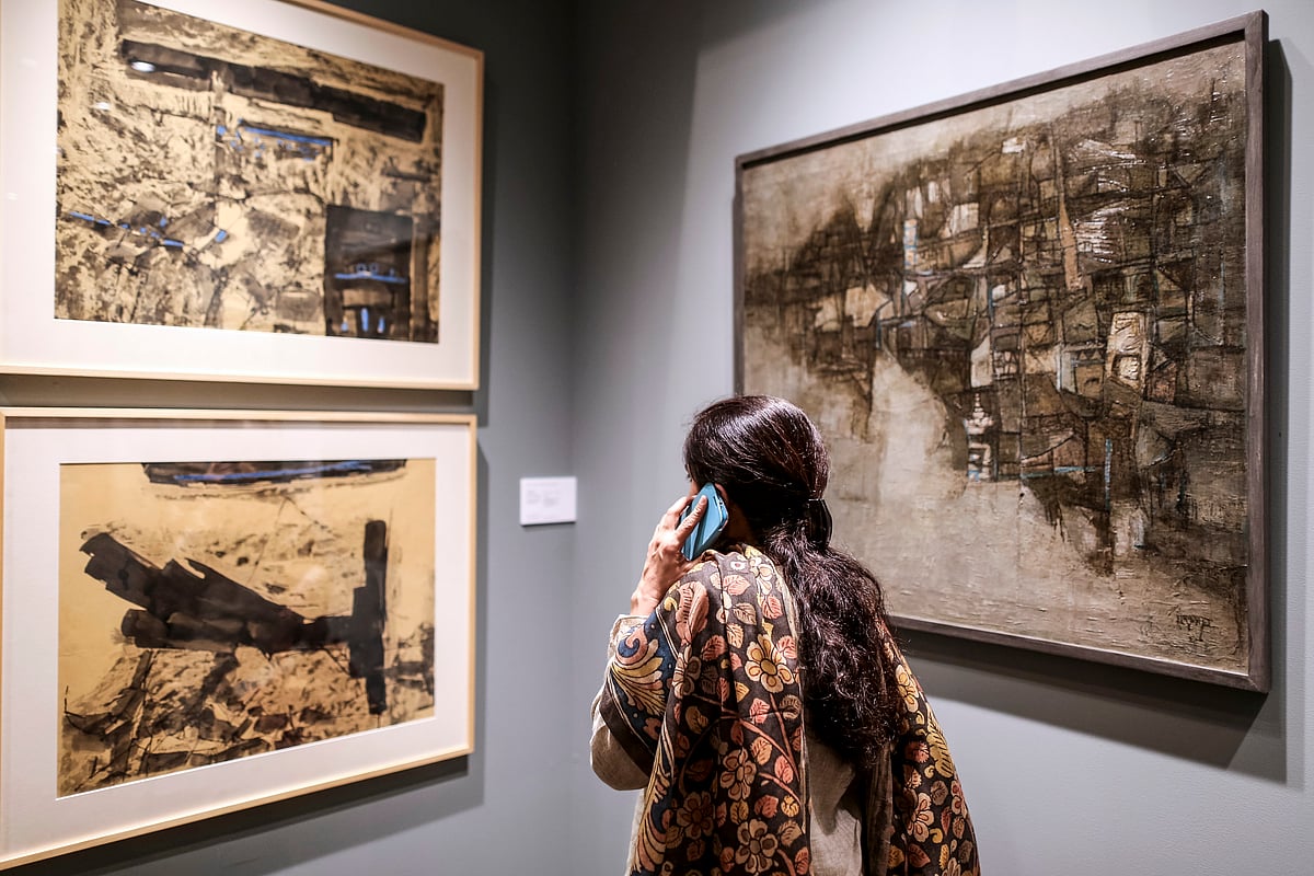 A visitor talks on the phone as she looks at paintings during the preview show of Christie’s South Asian Art auction in Mumbai. (Photographer: Dhiraj Singh/Bloomberg)