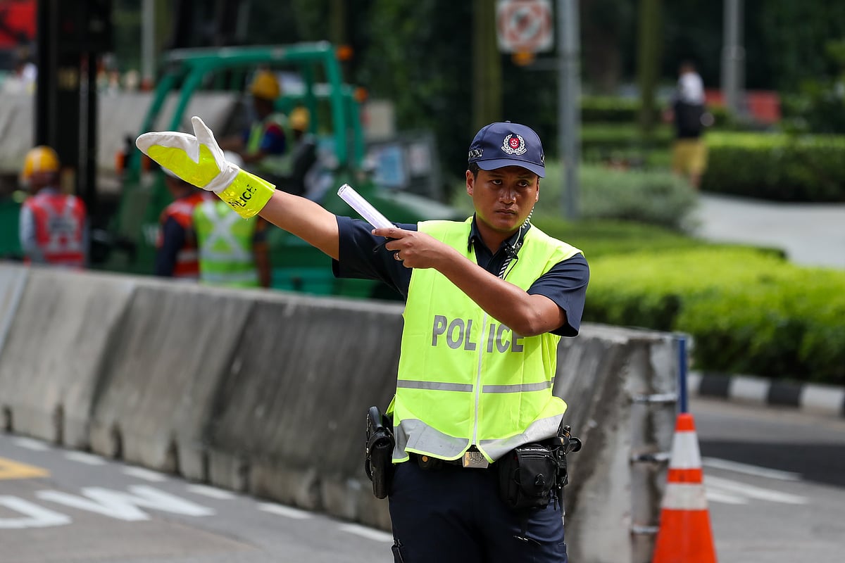 A police officer directs traffic in Singapore. (Photographer: SeongJoon Cho/Bloomberg)