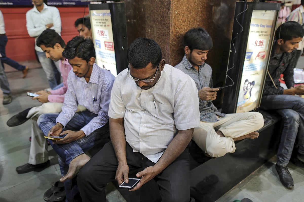 Commuters use smartphones in Mumbai. (Photographer: Dhiraj Singh/Bloomberg)