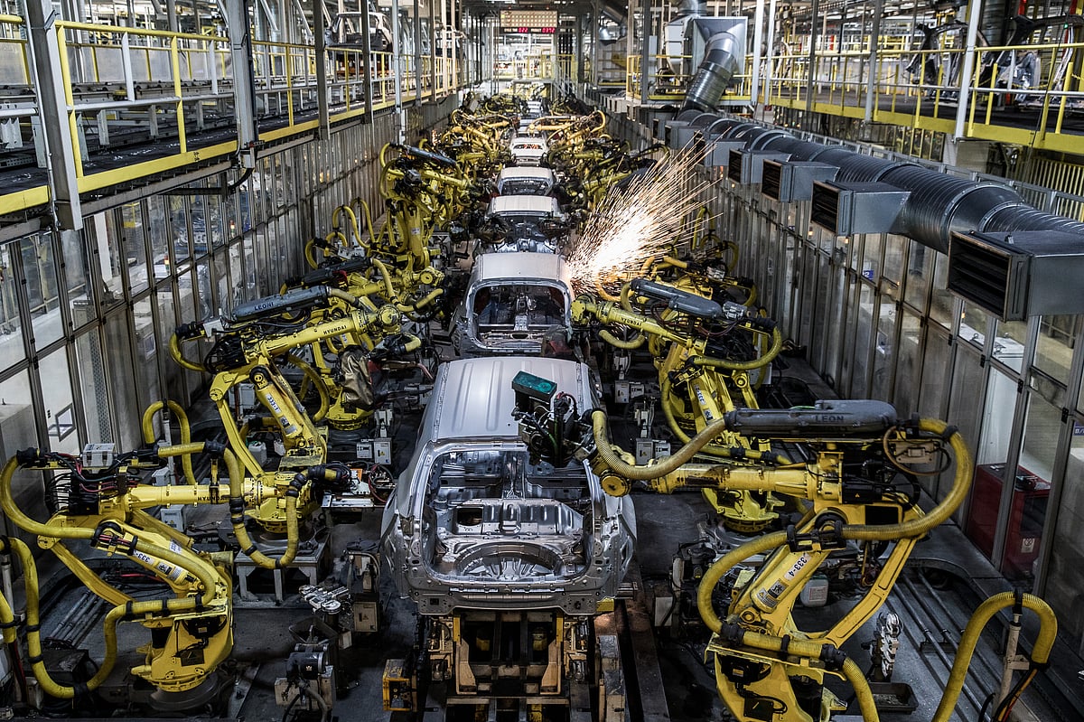 Robotic arms weld panels of automobiles on a production line. (Photographer: Akos Stiller/Bloomberg)