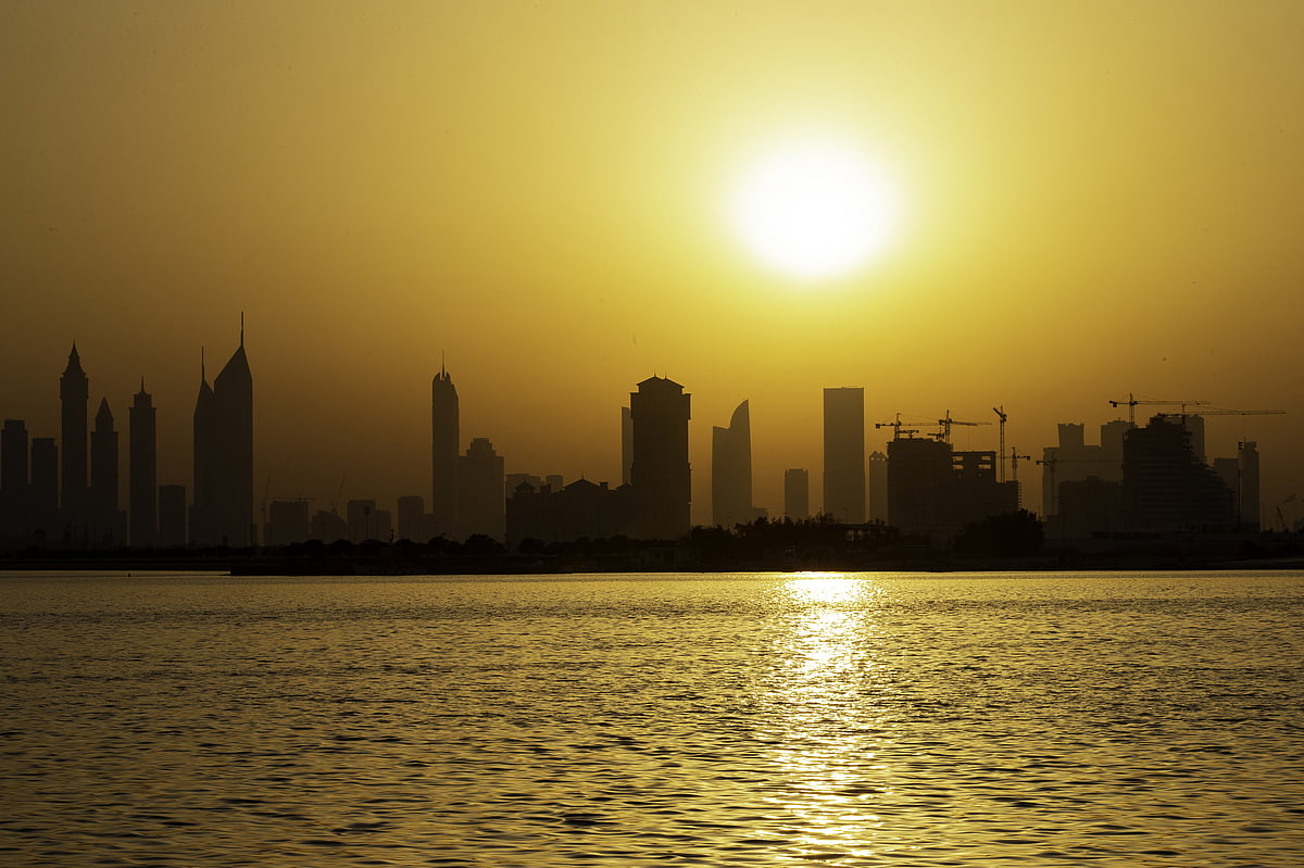 The sun silhouettes construction cranes and city skycrapers. Photographer: Christopher Pike/Bloomberg