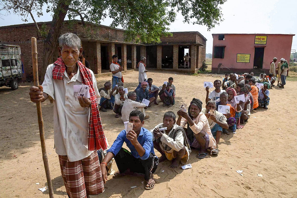 Voter show their identity cards as they wait in a queue to cast their votes at a polling station in Nawada district of Bihar. (Source: PTI)