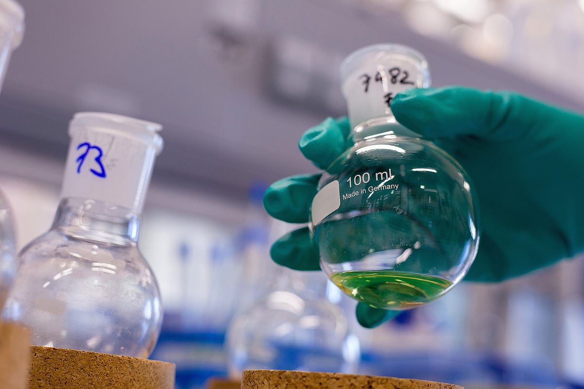 An employee holds a glass flask in a research laboratory. (Photographer: Krisztian Bocsi/Bloomberg)