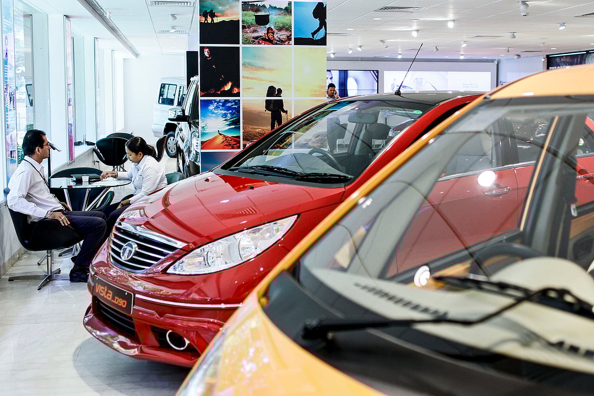 Sales assistants sit at a table beside a Tata Motors Ltd. Photographer: Dhiraj Singh/Bloomberg