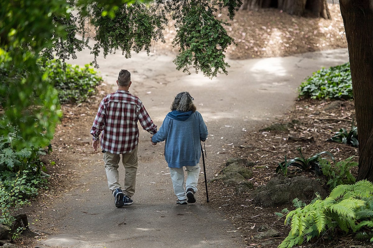 A elderly couple holds hands while walking on a path. (Photographer: David Paul Morris/Bloomberg)