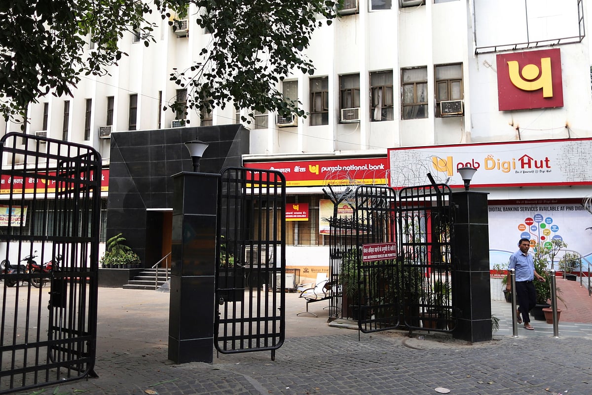 A pedestrian walks past a Punjab National Bank office building in New Delhi. (Photographer: Anindito Mukherjee/Bloomberg)