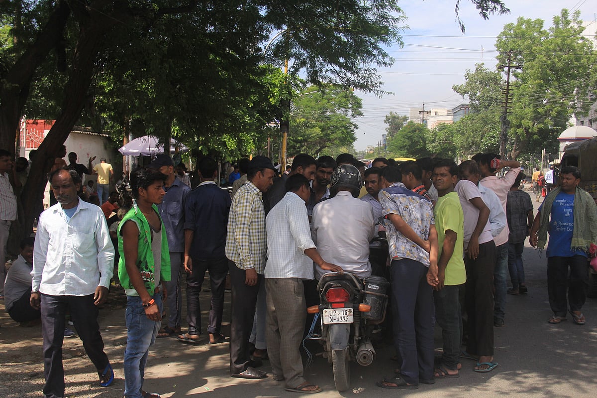 Skilled labourers surround a man (on two-wheeler) enquiring him for work at the Labour Chowk in Sector-5, Noida. (Photographer: Nishant Sharma/BloombergQuint)