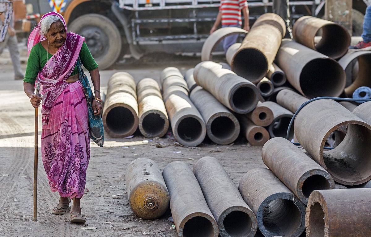 An elderly woman walks past metal pipes on a street in  New Delhi. (Photographer: Prashanth Vishwanathan/Bloomberg)