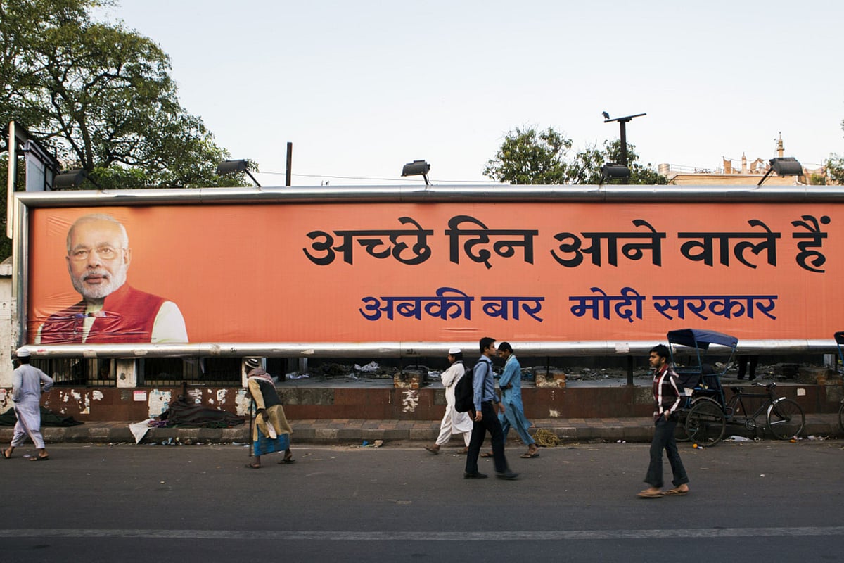 Pedestrians walk past a billboard for the BJP in New Delhi on April 10, 2014. (Photographer: Prashanth Vishwanathan/Bloomberg)