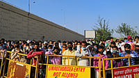 Migrant workers and their families stand behind a barrier at a police checkpoint in Delhi (Photographer: Anindito Mukherjee/Bloomberg)