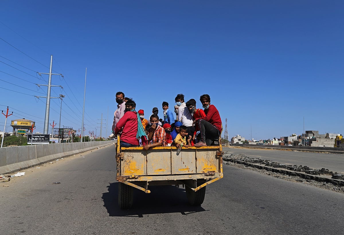 Migrant workers and their families sit in the back of a truck traveling along National Highway 24 during a lockdown (Photographer: Anindito Mukherjee/Bloomberg)