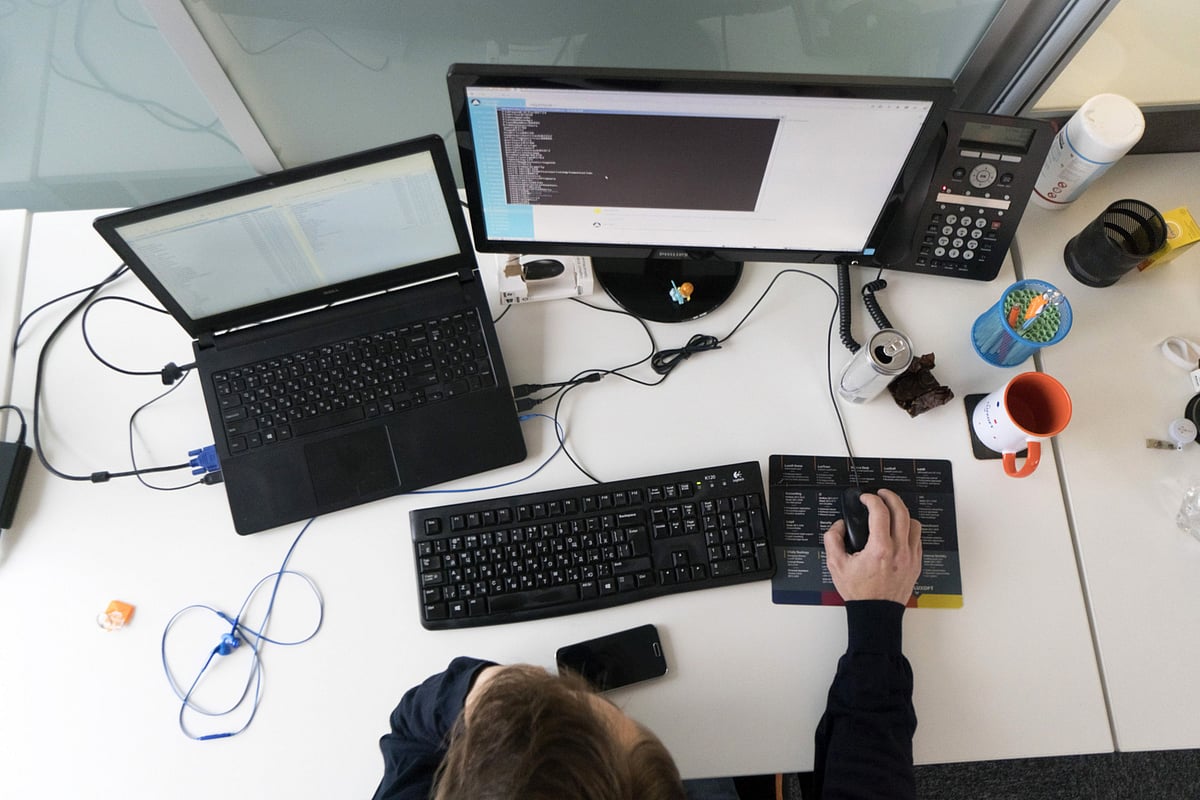 An employee uses a desktop computer and a laptop. (Photographer Vincent Mundy/Bloomberg)