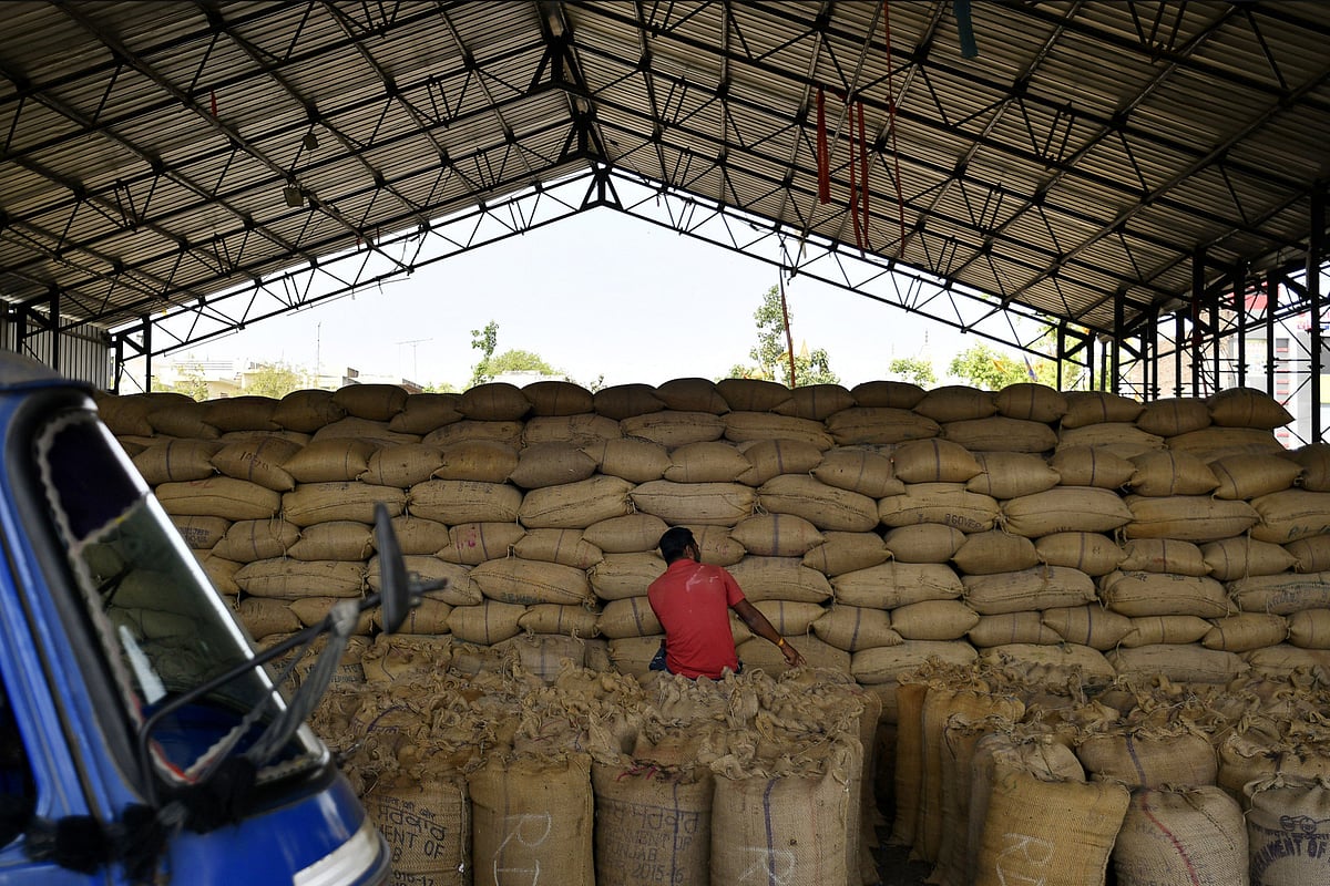 A man sits on sacks of grain at a wholesale grain market in Rewari, Haryana, India, on March 28, 2018. (Photographer: Anindito Mukherjee/Bloomberg)