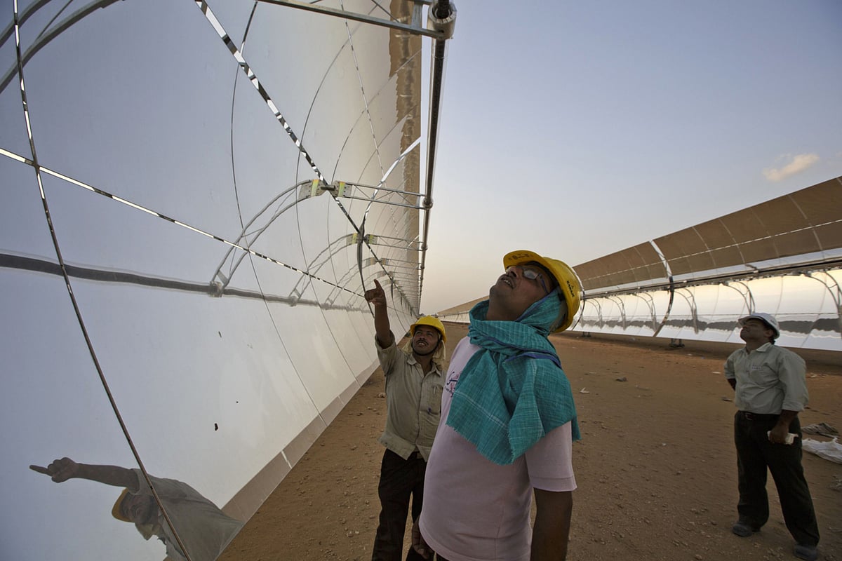 Workers inspect the reflector panels of a parabolic trough at a solar-thermal power plant,  near Nokh, Rajasthan. (Photographer: Kuni Takahashi/Bloomberg)