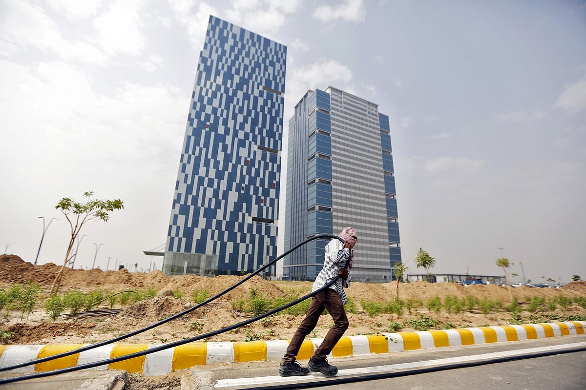 <div class="paragraphs"><p>A labourer pulls a cable in front of two office buildings in GIFT City at Gandhinagar, Gujarat. (Photo: Amit Dave/Reuters)</p></div>