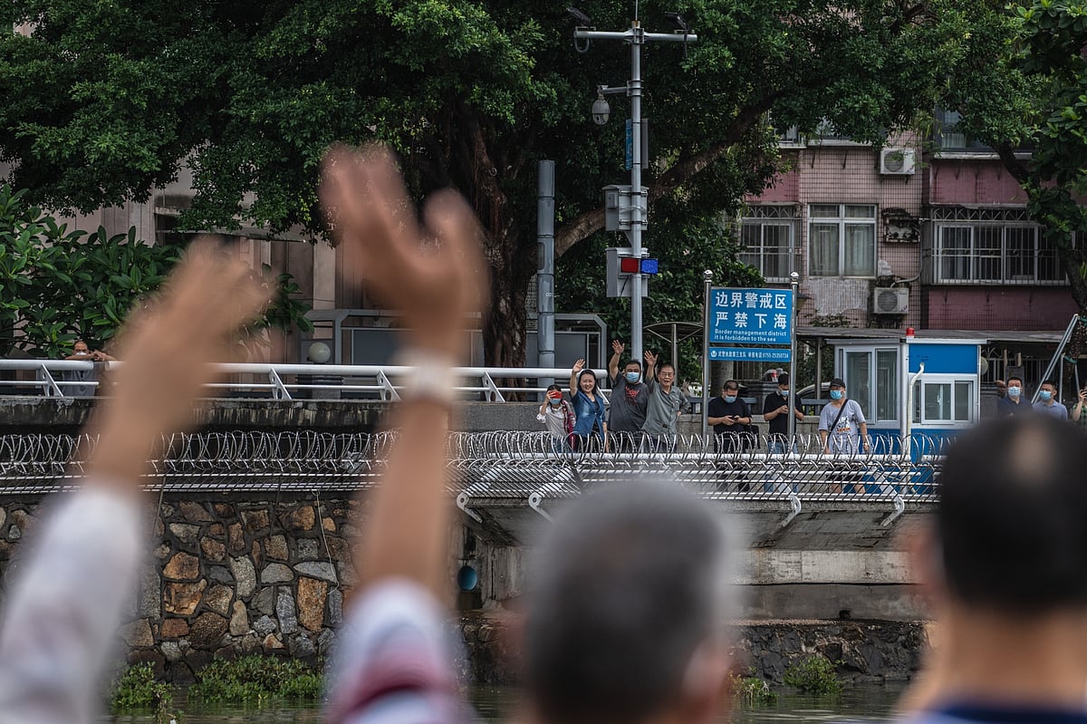 People in mainland China, back, wave across the border toward the closed town of Sha Tau Kok in Hong Kong, in June 2022.Photographer: Lam Yik/Bloomberg