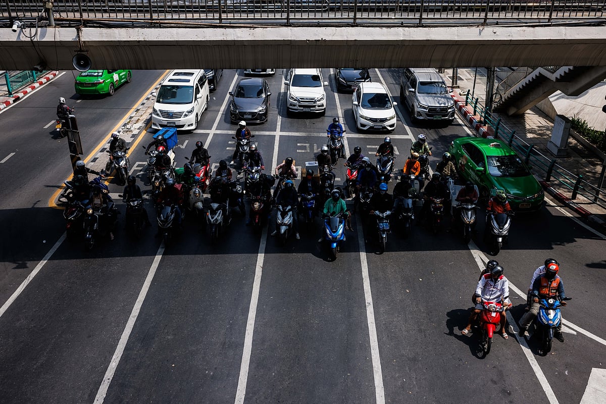 Motorcyclists gather in the shade as they wait at a traffic signal in Bangkok on May 18.Photographer: Andre Malerba/Bloomberg
