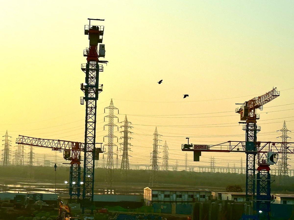 <div class="paragraphs"><p>Construction crane and power transmission towers seen against a backdrop of orange sky. (Photographer: Vishal Patel / Source: NDTV Profit)</p></div>